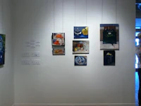 a group of paintings hanging on a wall in an art gallery