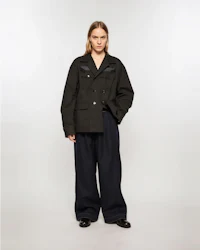 the model is wearing a black jacket and wide leg pants