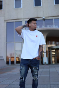 a man wearing ripped jeans and a white t - shirt