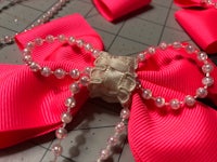 a pink bow with pearls and beads on a cutting board