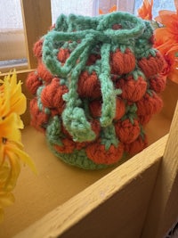 an orange and green crocheted bag sitting on a shelf
