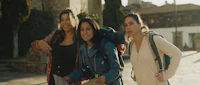 three women with backpacks walking down a street