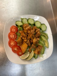 a plate of chicken salad with tomatoes and cucumbers