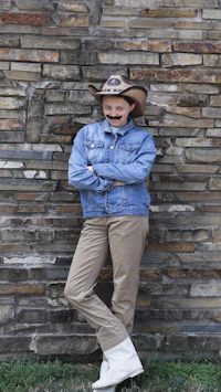a man wearing a cowboy hat leaning against a brick wall