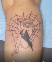 a woman with a spider web tattoo on her thigh