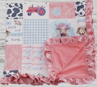 a pink blanket with ruffles and a tractor on it