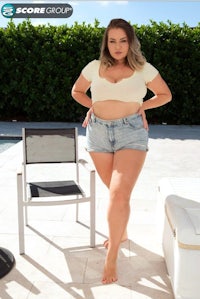 a woman in denim shorts posing in front of a chair