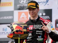 a man holding a red bull racing helmet in front of a podium