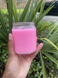 a person holding a pink candle in front of a palm tree