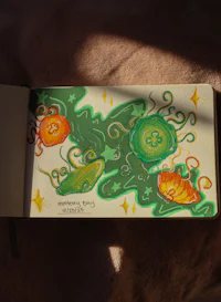 an open notebook with a drawing of a green flower
