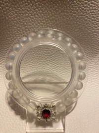a clear mirror with a red stone on it