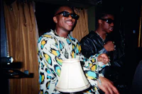 a man in a colorful shirt is standing next to a lamp