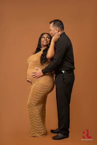 a pregnant couple posing in front of a brown background