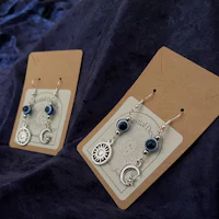 a pair of earrings with blue eyes and a crescent moon