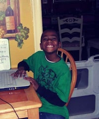 a boy sitting at a table with a laptop