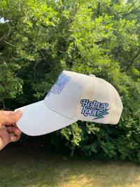 a woman is holding a white hat with a tree on it