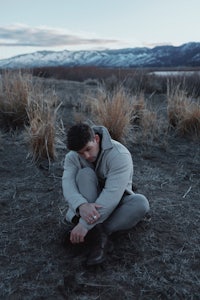 a man sitting in the middle of a field