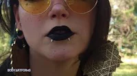 a woman in sunglasses with black lips and piercings