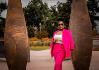 a woman in a pink suit standing in front of sculptures