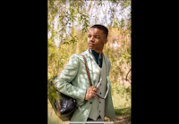 a young man in a green suit holding a bag