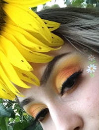 a woman with a sunflower on her face