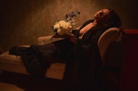 a woman laying on a chair holding a bouquet of flowers