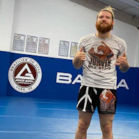 a man with a beard posing for a picture in a gym