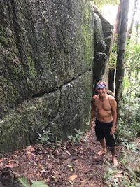 a man standing next to a large rock in the jungle