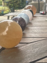a row of different colored crystal balls on a wooden table
