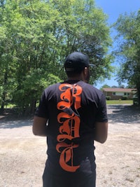 a man wearing a black t - shirt with orange lettering