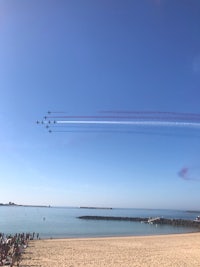 a group of red and white planes flying over a beach