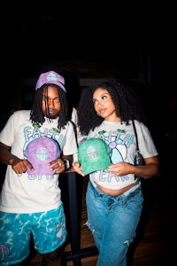 two people standing next to each other holding hats