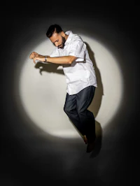 a man in a white shirt is jumping in front of a light