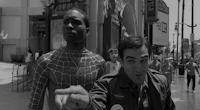 a man in a spider - man costume standing next to another man