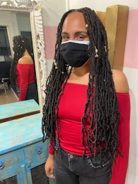 a woman wearing a mask and dreadlocks in front of a mirror