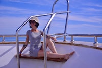 a woman sitting on a railing on a boat