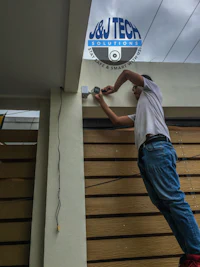 a man installing a security camera on a house