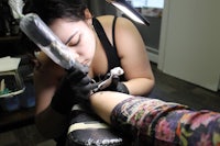 a woman is getting a tattoo on her arm