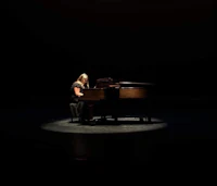 a woman playing a piano in a dark room