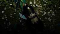 a bottle laying in the grass with butterflies on it