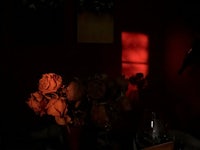 a vase of roses on a table in front of a red wall