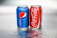 two cans of pepsi on a metal surface