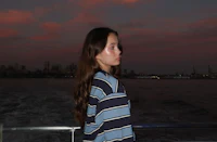 a young woman standing on a boat at dusk