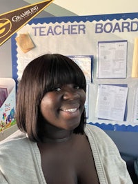 a woman smiling in front of a bulletin board
