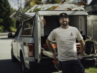a man standing in front of a white van with tools in it