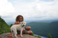 a man sitting on a rock with a dog