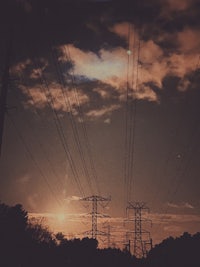 a sunset with power lines and clouds in the background