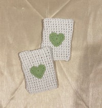 two crocheted heart shaped coasters on a bed