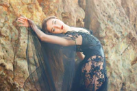 a woman in a black dress posing in front of rocks
