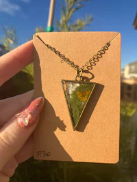 a person holding a necklace with a triangle on it